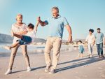 Balançoire, grands-parents et un enfant marchant sur la plage lors de vacances en famille, de vacances ou d’aventure en été. Jeune garçon enfant tenant la main d’un homme et d’une femme âgés à l’extérieur avec une énergie ou un jeu amusant.