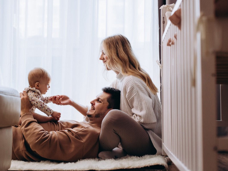 Les parents joyeux jouant avec leur petite fille sur le sol à la maison.