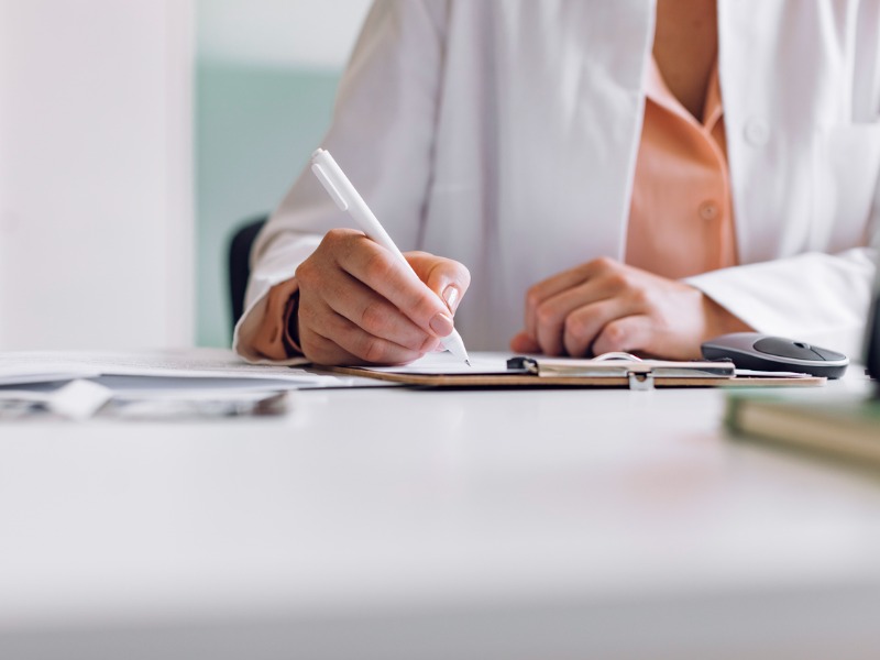 Main d’un docteur féminin méconnaissable écrivant un rapport médical.