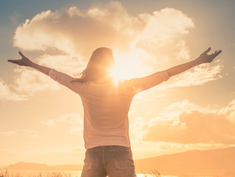 Jeune femme avec les mains levées la lumière du soleil du matin trouver le bonheur, la paix et l’espoir dans la nature.