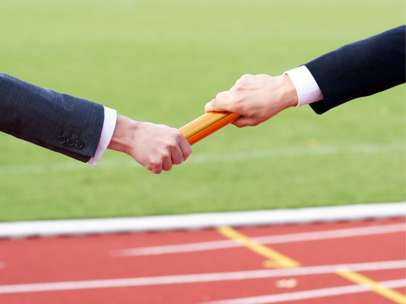 Les hommes d’affaires passent le bâton dans la course de relais dans le stade