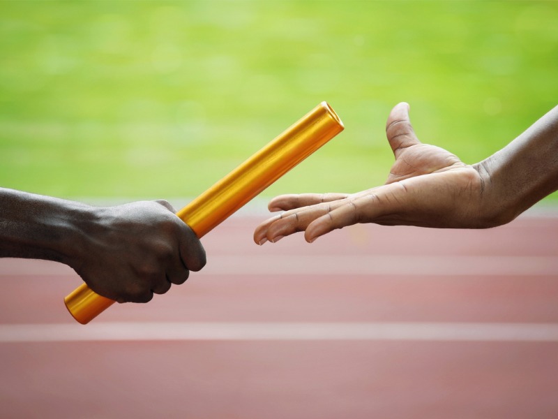 Des hommes se passent le bâton dans une course de relais dans un stade