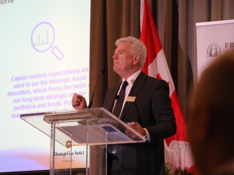 Ian Riach sur une scène donnant une conférence.